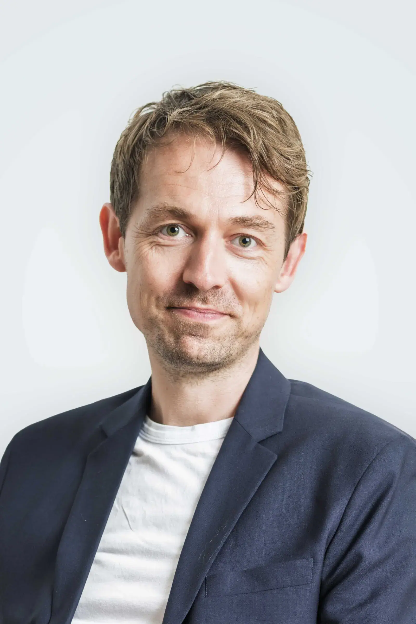 Jakob Damgaard, fotograf hos Skovgaard & Damgaard, i mørkeblå blazer og hvid T-shirt