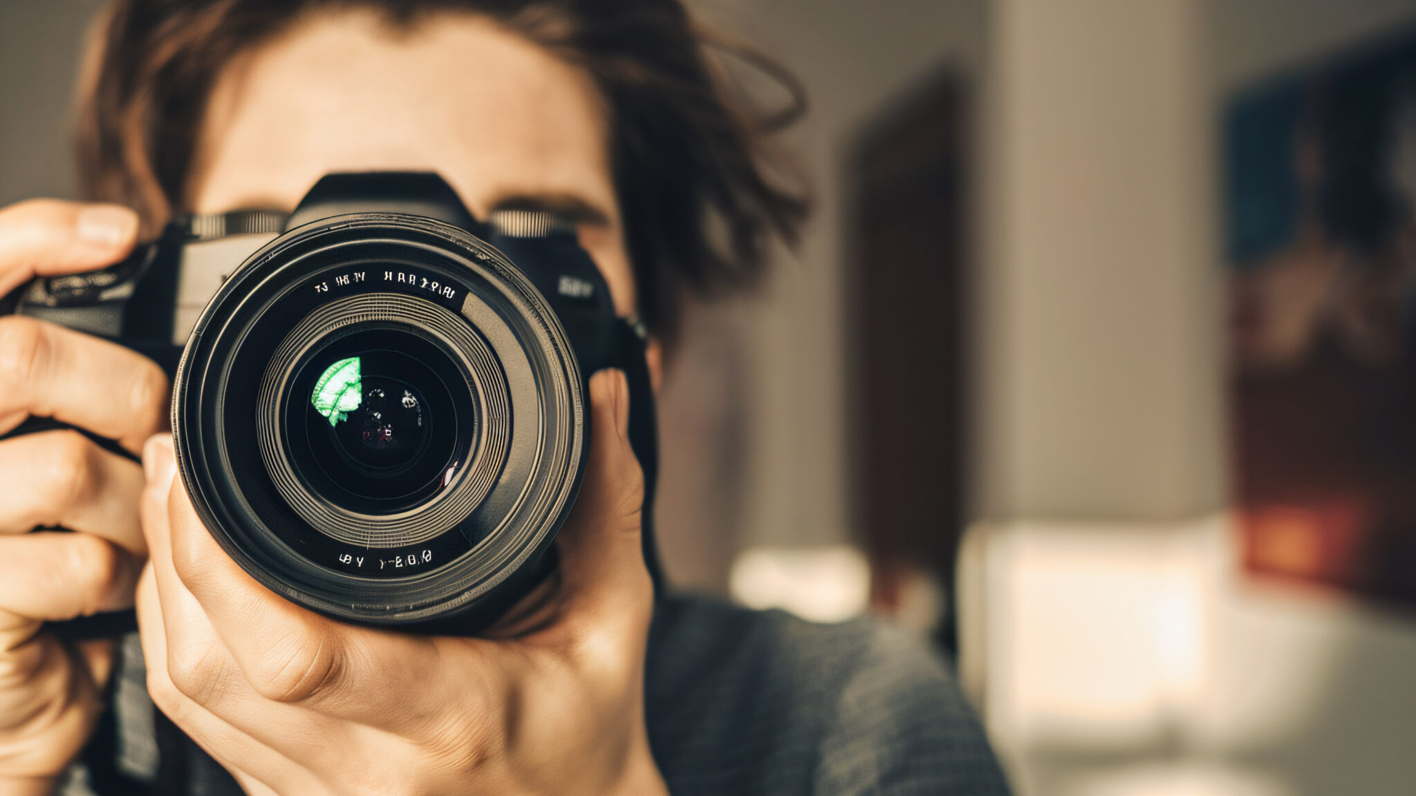 En person fotograferer med et spejlreflekskamera, linsen er i fokus. | Fotograf i Aarhus af Skovgaard & Damgaard