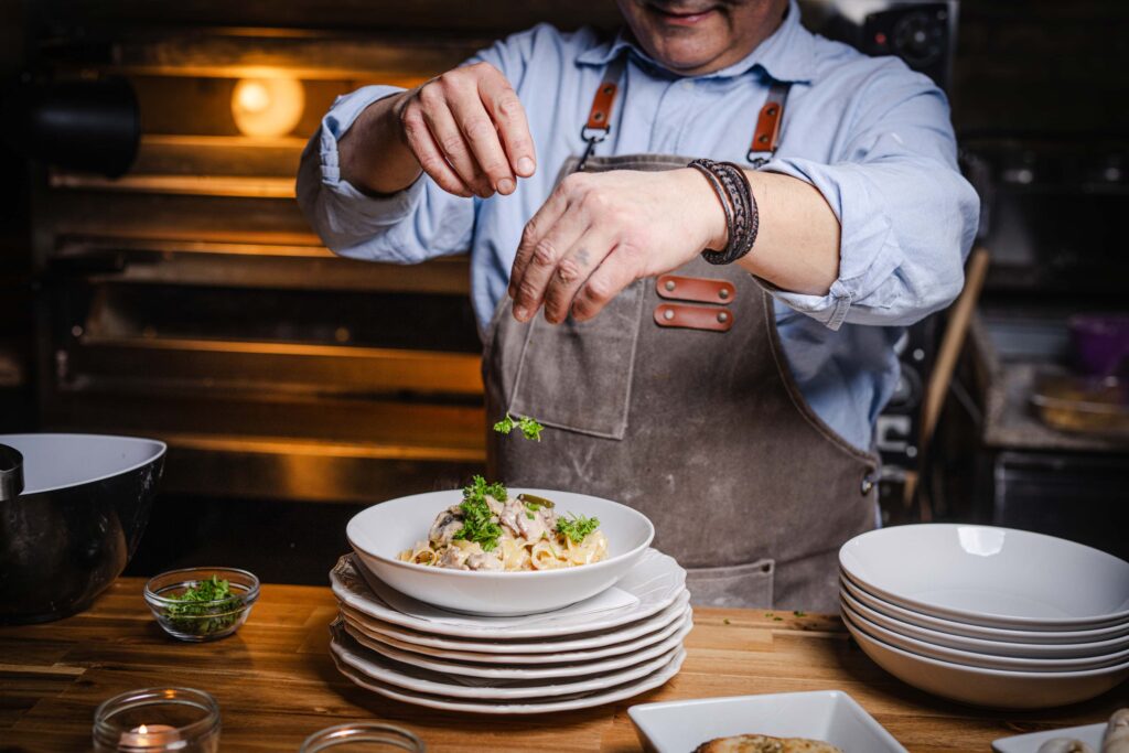 Kok pynter en tallerken med frisk pasta og urter p&aring; Ceres Trattoria.