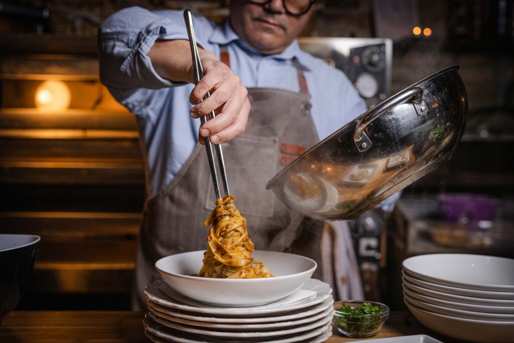 Kok serverer frisklavet pasta p&aring; Ceres Trattoria i en varm og autentisk italiensk atmosf&aelig;re.