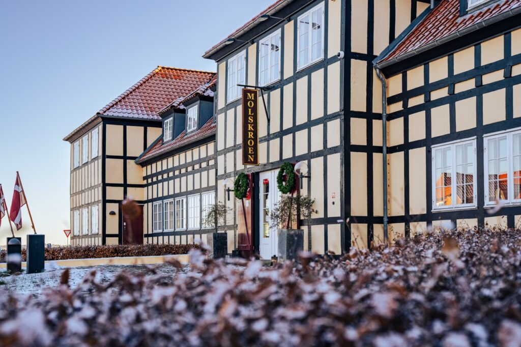 Erhvervsfotografering af Skovgaard & Damgaard – Molskroen med traditionel bindingsværksarkitektur og hyggelig atmosfære Erhvervsfoto af Molskroen med traditionel bindingsværksarkitektur og hyggelig facade, fotograferet af Skovgaard & Damgaard.