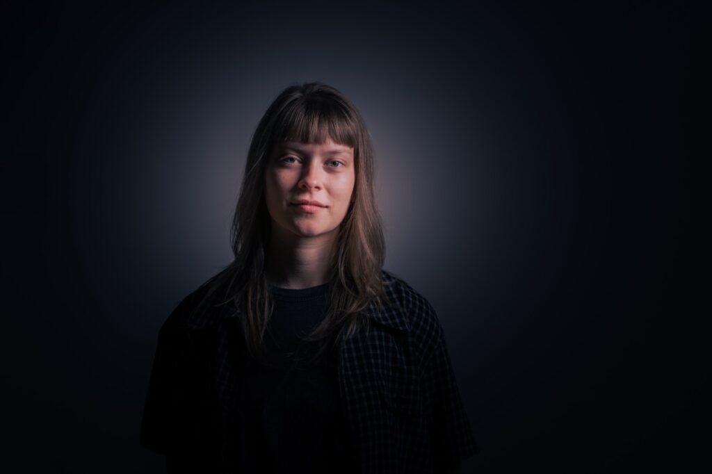 Portræt af sangerinde Alex Medhurst i mørkt studie med blødt lys, fotograferet af Skovgaard &amp; Damgaard.