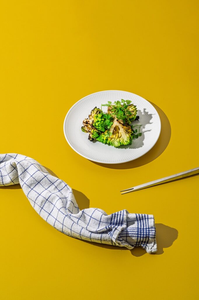 Vegetarisk servering med grillet romanesco og friske krydderurter på hvid tallerken – professionelt madfoto af Skovgaard &amp; Damgaard