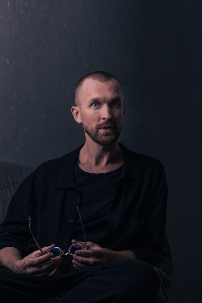 Portræt af en psykoterapeut siddende med briller i hånden i et roligt miljø, fotograferet af Skovgaard &amp; Damgaard.