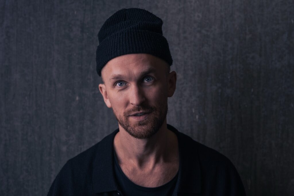 Portrætfotografering af Skovgaard & Damgaard – professionelt erhvervsportræt i stemningsfuldt miljø Erhvervsportræt af en person foran mørk baggrund, fotograferet af Skovgaard & Damgaard.