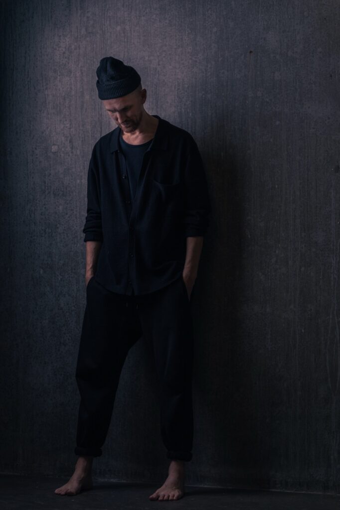 Helkropsportræt af psykoterapeut i et mørkt og minimalistisk miljø, fotograferet af Skovgaard &amp; Damgaard.