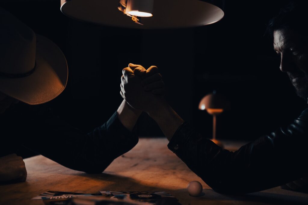 Erhvervsfotografering af Skovgaard & Damgaard – dramatisk armlægningskamp i dystopisk lyssætning for The Powls’ Tortour-kampagne To personer i en dramatisk armlægning under dystopisk belysning, fotograferet som en del af The Powls’ Tortour-kampagne af Skovgaard & Damgaard.