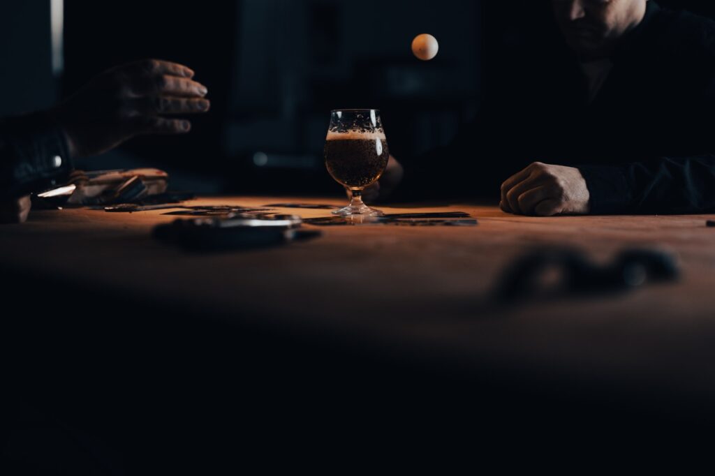 Erhvervsfotografering af Skovgaard & Damgaard – absurd bordtennisboldspil og ølglas i dystopisk kampagne for The Powls’ Tortour Absurd scene med bordtennisbold, ølglas og dystopisk belysning fra The Powls’ Tortour-kampagne, fotograferet af Skovgaard & Damgaard.