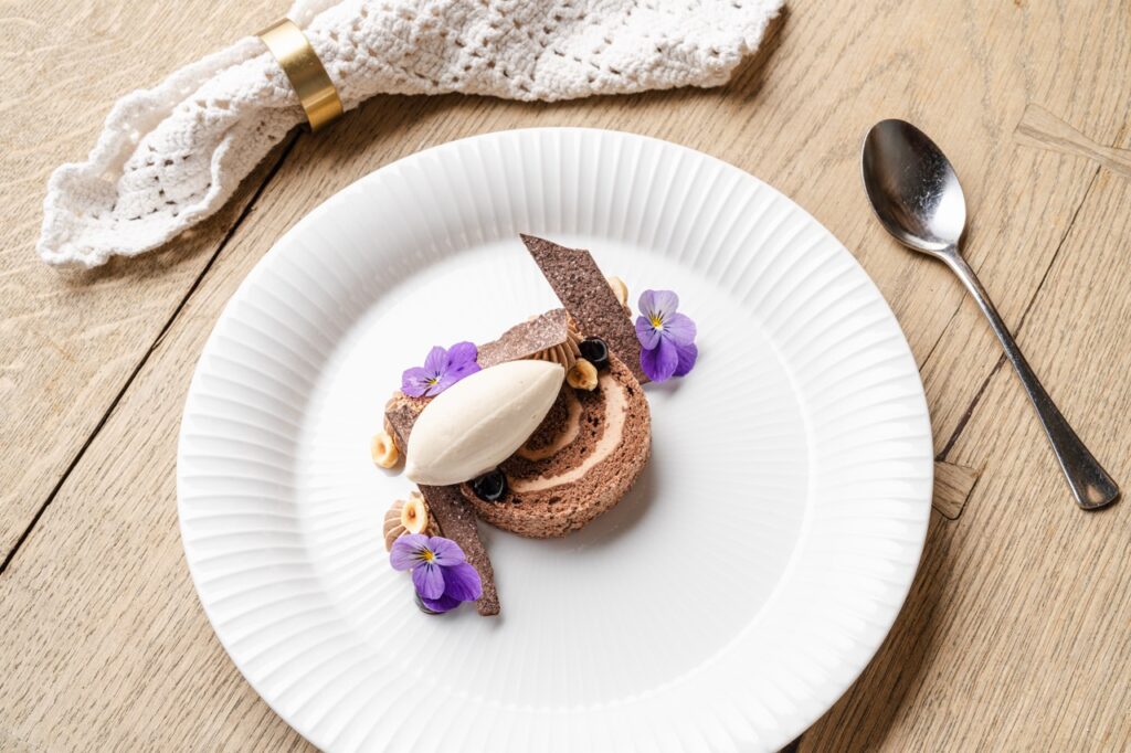 Madfotografering af Skovgaard & Damgaard – gourmetdessert med Kastbergs Is lavet af tidligere landsholdskok Sisse Pernille Busk Gourmetdessert med Kastbergs Is, anrettet med chokolade, blomster og sprøde elementer, fotograferet af Skovgaard & Damgaard.