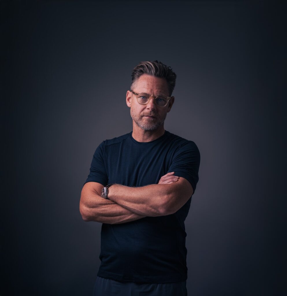 Portrætfotografering af Skovgaard & Damgaard – erhvervsportræt af skuespiller Paw Henriksen til et projekt om kunstens rolle i erhvervslivet Stilrent studieportræt af skuespiller Paw Henriksen med korslagte arme, fotograferet af Skovgaard & Damgaard.