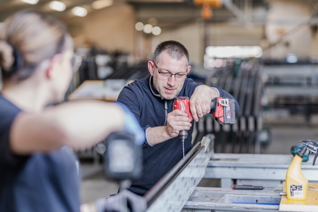Erhvervsfotografering af Skovgaard & Damgaard – medarbejderportræt og præcist samarbejde hos AS Facader Erhvervsportræt af medarbejdere hos AS Facader, der samarbejder om præcist håndværk med avanceret værktøj, fotograferet af Skovgaard & Damgaard.