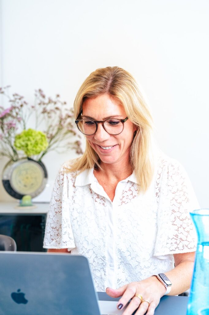 Smilende psykolog ved computer i lyse lokaler hos Neuropsykologisk Praksis, fotograferet af brandingfotograf Skovgaard &amp; Damgaard.