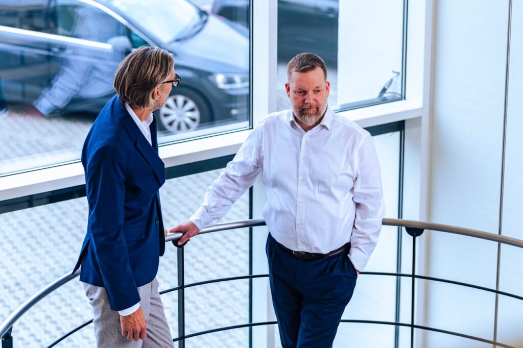 Steffen Skovfoged og Rasmus Blok i strategisk samtale hos UNIwise i moderne kontormilj&oslash;, erhvervsfotograferet af Skovgaard &amp; Damgaard.